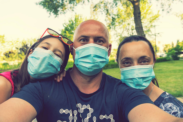 Familia en máscaras médicas protectoras. Madre, padre, hija protéjanse del virus Coronavirus. Familia en máscaras médicas al aire libre. De cerca. tonificado - Foto, imagen
