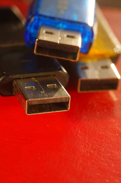 USBフラッシュドライブ-赤の背景に黒、黄色、青。3台の中古コンピュータのフラッシュドライブ、動作するように準備ができました。明るい背景にいくつかの色で、データメモリスティックのクローズアップ. - 写真・画像