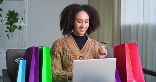 Teljes hosszúságú afro amerikai göndör lány online vásárlás, miközben otthon ül a laptop mutatja hitelkártya pénzzel teszi gesztus rendben szimbóluma sietős vásárolni kiváló választás, e-kereskedelmi koncepció - Felvétel, videó