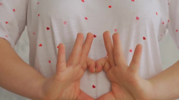 Primer plano de la atractiva adolescente con síndrome de Down haciendo un corazón con las manos - Metraje, vídeo