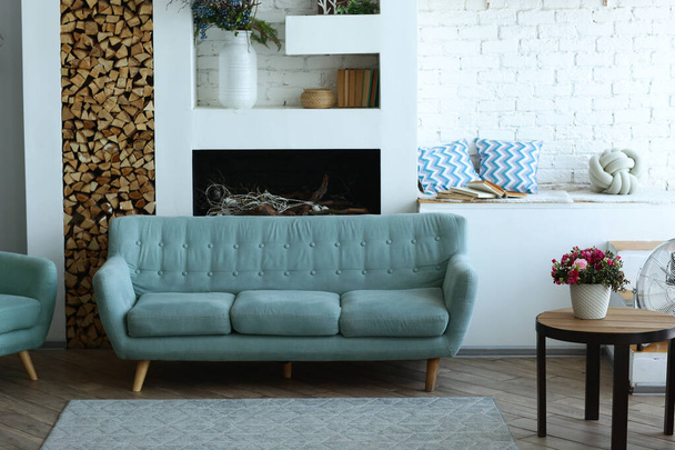 青いソファ、暖炉、ポット植物、カーペットやテーブルとかわいい現代の寝室のインテリア - 写真・画像