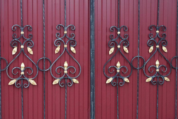 металева текстура кованих чорних стрижнів з візерунком на залізній червоній стіні паркану
 - Фото, зображення