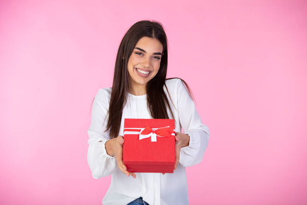 Young woman portrait hold gift. Smiling happy girl on pink background. Cheerful beautiful woman and charm gift decoration joy party.  Attractive young woman holding gift boxes over pink background - Foto, immagini