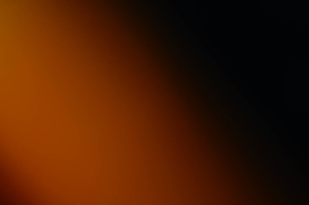 オレンジと黒のにじんだ抽象的な背景。テキストとグラフィックのための蜂蜜色の地平線。光から闇へのソフト遷移。燃える炎と輝く輝き.   - 写真・画像