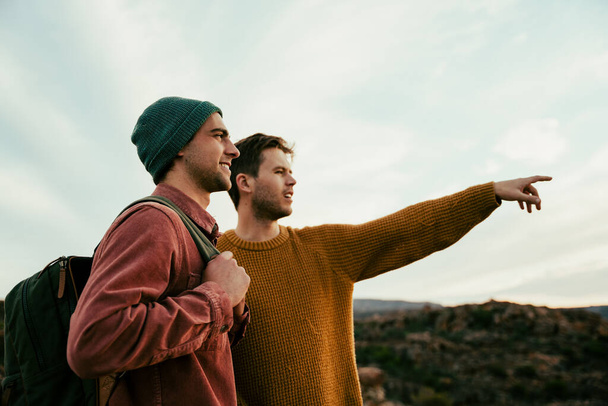 Two caucasian males hiking in wilderness pointing into distance enjoying the outdoors - Foto, Bild