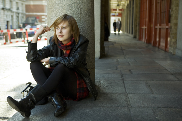 young attractive girl with red hair sitting on street, waiting.  - Foto, afbeelding