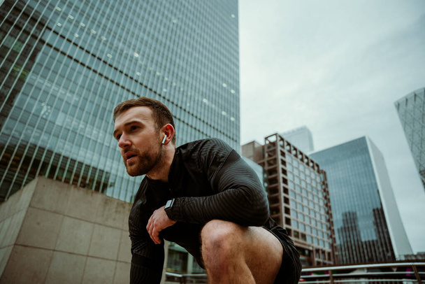 Καυκάσιος αθλητής που ετοιμάζεται να τρέξει ενώ προπονείται στην πόλη - Φωτογραφία, εικόνα