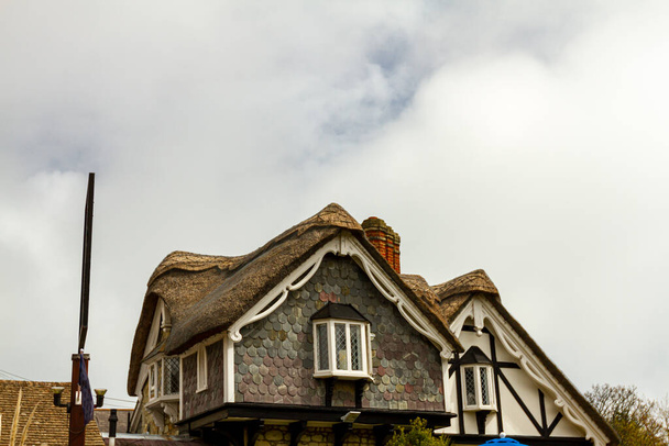 Close-up beeld van een vintage huis met rieten daken. Deze traditionele dakstijl houdt in dat droge rietjes op een georganiseerde manier worden gelegd en bedekt met een metalen vlies om de vorm te behouden.. - Foto, afbeelding