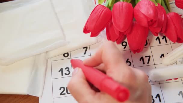 Közelkép női kéz jelöli a menstruáció napjait a naptári időszakban. - Felvétel, videó