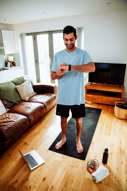 Homme d'affaires métis vérifiant l'état de forme physique sur smartwatch après l'exercice d'étirement  - Photo, image