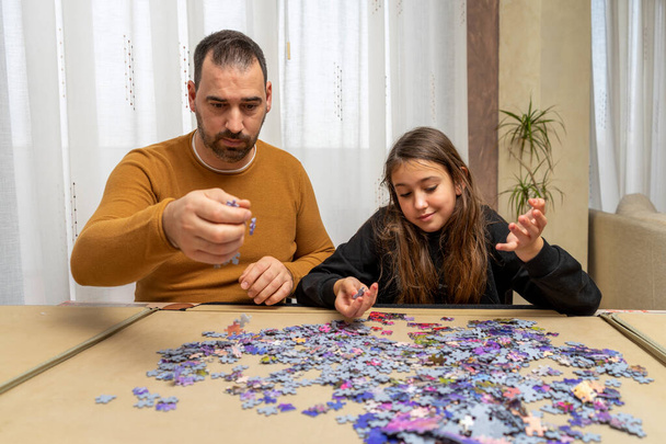 Vater und Tochter sind niedergeschlagen von der Schwierigkeit, in ihrem Wohnzimmer ein Puzzle zusammenzusetzen. Heimkonzept - Foto, Bild