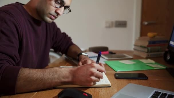 Gemischte Rasse Geschäftsmann mit Stift Schreiben auf Notizblock Sortieren Admin während der Arbeit von zu Hause aus - Filmmaterial, Video