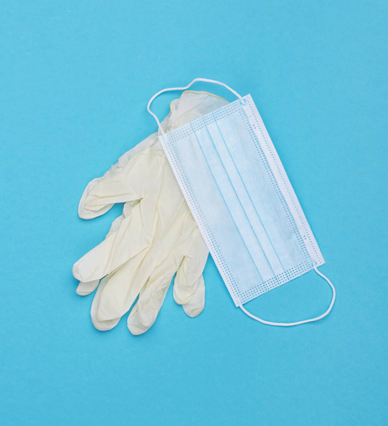 Masque facial et gants en latex. Prévention du coronavirus masque chirurgical médical avec gants de protection en latex. Sur fond bleu. - Photo, image