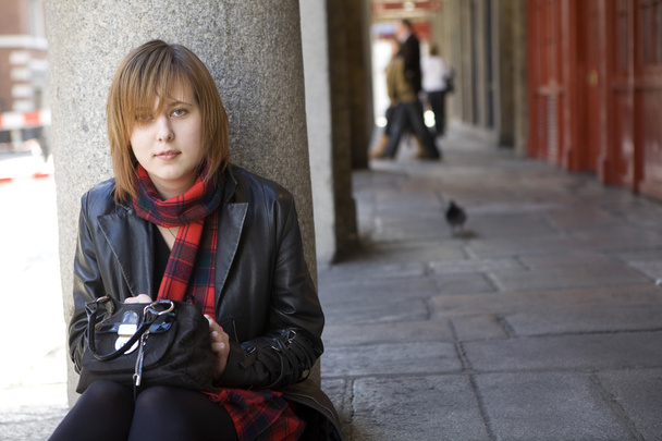 mladá atraktivní dívka s rudými vlasy sedí na ulici, čeká.  - Fotografie, Obrázek