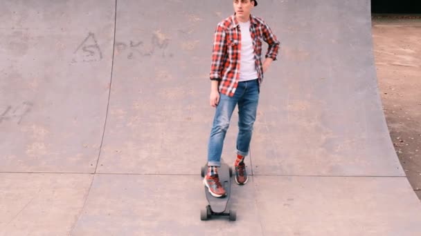 Mladý skateboardista stojící na rampě v džínách, kostkované košili a baseballové čepici, zpomalený pohyb - Záběry, video