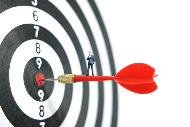 Üzleti stratégia konceptuális fotó - Miniatűr üzletember áll a piros nyíl felett egy dartboard - Fotó, kép