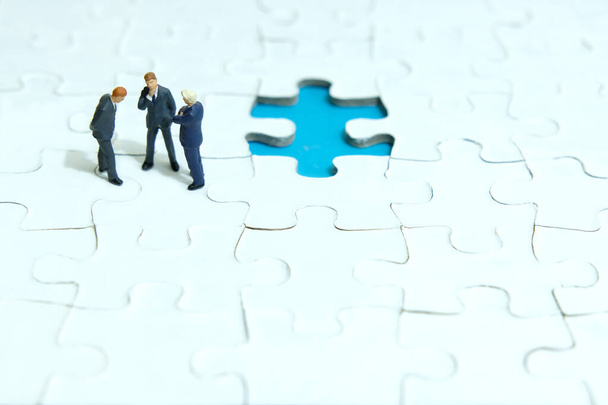 Business strategy conceptual photo - three miniature businessman discussion above missing puzzle jigsaw - Photo, Image
