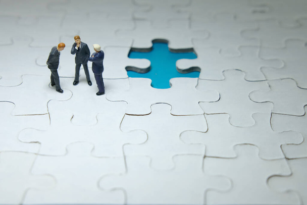 Strategia biznesowa koncepcyjne zdjęcie - trzy miniaturowe dyskusje biznesmena powyżej brakuje puzzle układanki - Zdjęcie, obraz