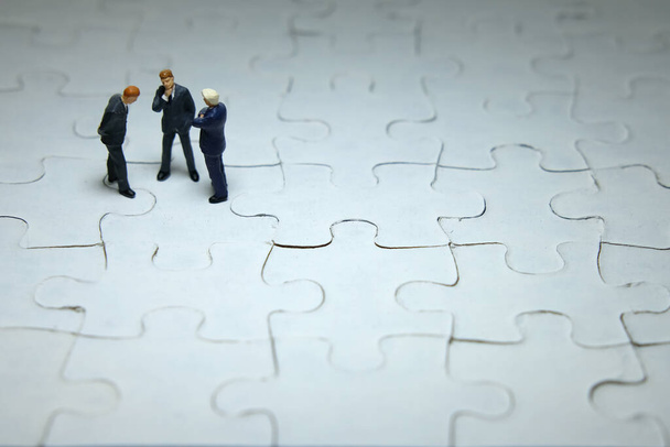 Концептуальная фотография бизнес-стратегии - три миниатюрные дискуссии бизнесмена над головоломкой - Фото, изображение