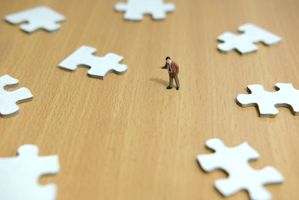 Business strategy conceptual photo - miniature businessman pointing on missing piece puzzle - Foto, afbeelding