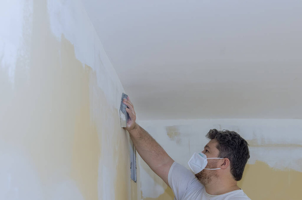Szlifowanie ścian gipsowo-kartonowych za pomocą pacy piaskowej podczas remontu domu w pomieszczeniu - Zdjęcie, obraz