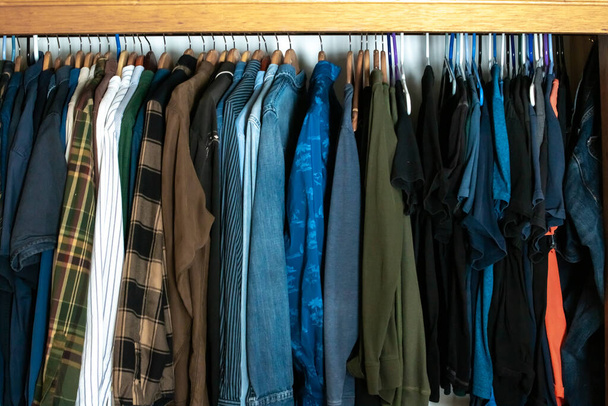 Um armário cheio de camisas de mangas compridas e flanelas penduradas em um feixe de cedro em Londres, Ontário, Canadá, 2021. - Foto, Imagem