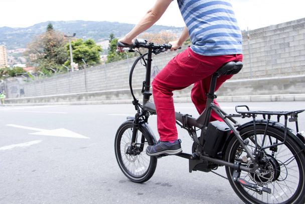 Zbliżenie do tyłu człowieka pedałującego na rowerze elektrycznym w mieście Medellin - Zdjęcie, obraz