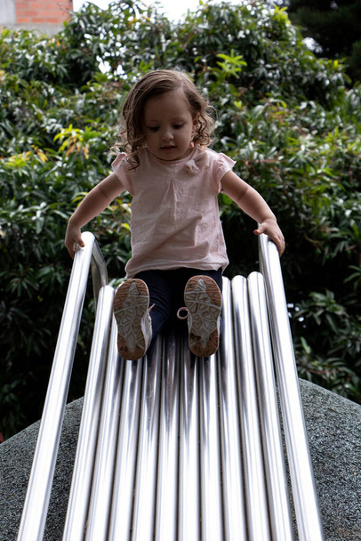 Kleines Mädchen in rosa Hemd und Jeans spielt im Zement- und Metallpark - Foto, Bild