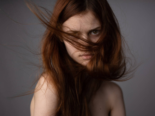 face of a red-haired woman on a gray background bare shoulders close-up model - Fotó, kép
