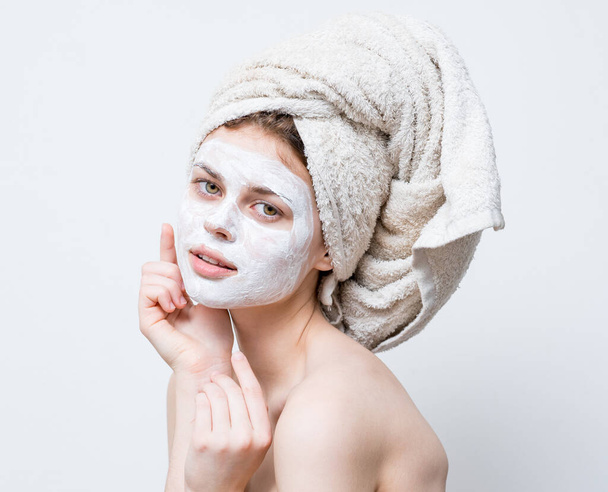 γυναίκα με κρέμα στο πρόσωπό της πετσέτα στο κεφάλι φροντίδα του δέρματος - Φωτογραφία, εικόνα