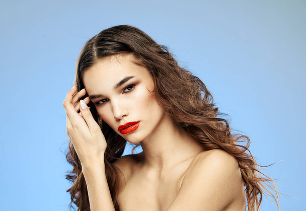 Female model curly hair brunette red lips shadows on the eyelids bared shoulders close-up - Foto, imagen