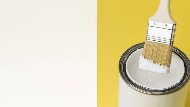 Pinsel mit tropfender weißer Farbe über ein Glas auf weißem und gelbem Hintergrund. Ausführung von Malerarbeiten. Platz für Text. - Foto, Bild