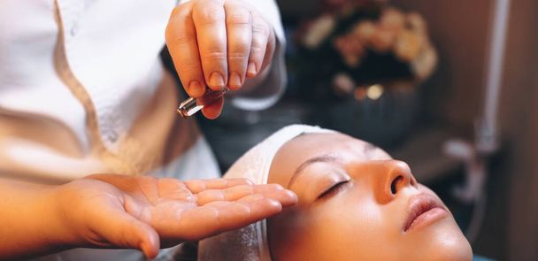 Massaggiatore caucasico mettere un po 'di olio da massaggio sulla palma avendo una sessione di massaggio facciale - Foto, immagini