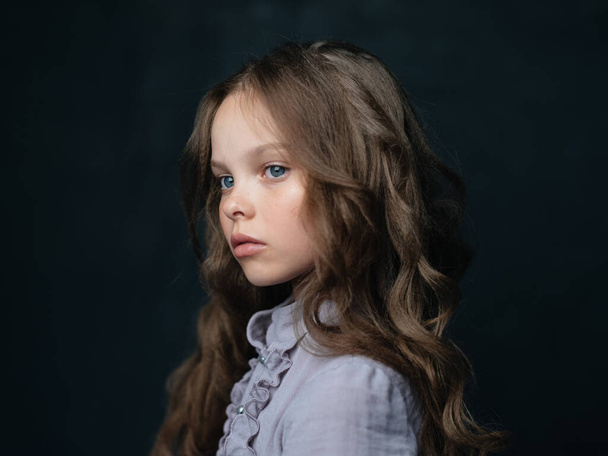 muotokuva kaunis tyttö harmaa mekko tumma tausta ja kihara tukka siniset silmät - Valokuva, kuva