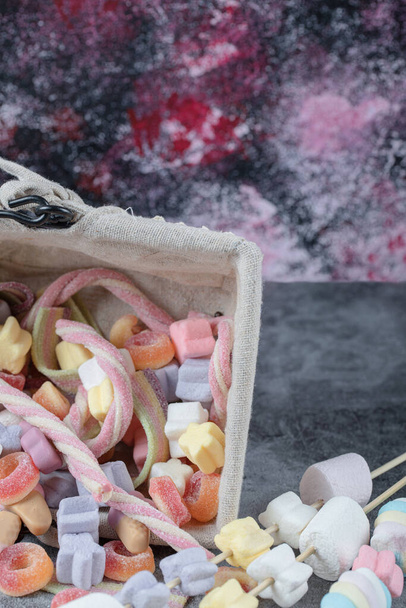 Marshmallow multicolore e gelatine si mescolano in un cestino rustico. Foto di alta qualità - Foto, immagini
