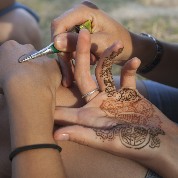 A woman making temporary henna tattoo on woman's wirst - Zdjęcie, obraz