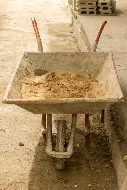 Een kleine zandkar heeft een enkel wiel om de arbeid van de binnenlandse arbeiders te vergemakkelijken. - Foto, afbeelding
