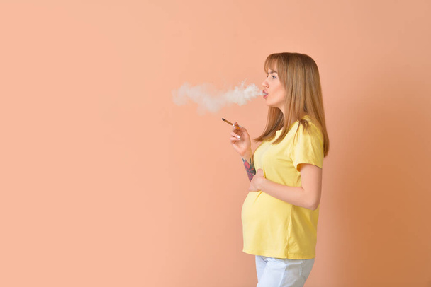 Fumar mujer embarazada sobre fondo de color - Foto, imagen