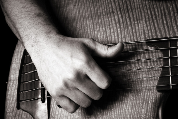 Playing six-string electric bass guitar; slap technique, right hand; toned monochrome image - Photo, Image