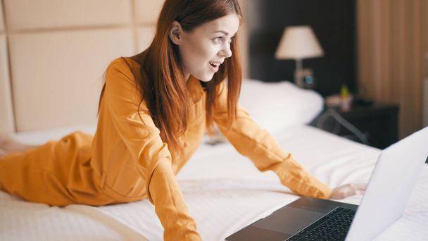 mulher alegre no quarto encontra-se na cama em frente à comunicação laptop - Foto, Imagem