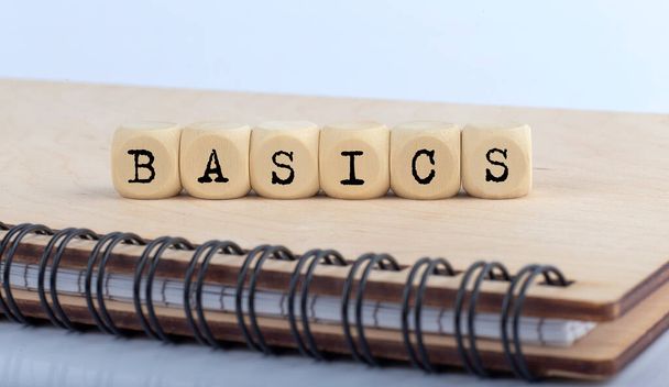 palabra BASICS hecha con letras en bloques de madera en el bloc de notas de madera - Foto, imagen