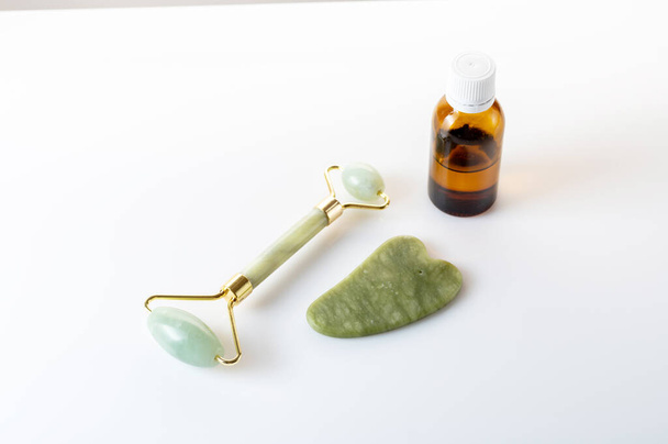 Rodillo de masaje y piedra de jade para suavizar las arrugas. Rodillo de masaje y aceite. - Foto, Imagen