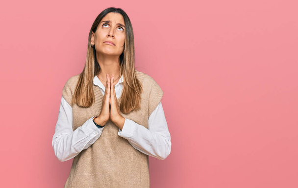 Jonge vrouw draagt casual kleding bedelend en biddend met handen samen met hoop uitdrukking op gezicht zeer emotioneel en bezorgd. bedelen.  - Foto, afbeelding