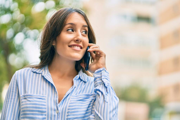 Молода іспаномовна жінка посміхається щаслива розмова на смартфоні в місті
. - Фото, зображення