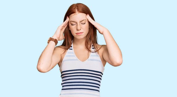 Młoda kobieta czytająca w ubraniach bez zobowiązań z ręką na głowie na ból głowy, ponieważ stres. migrena.  - Zdjęcie, obraz