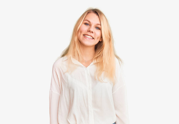 Nuori kaunis blondi nainen päällään rento paita näyttää positiiviselta ja onnelliselta seisoo ja hymyilee luottavainen hymy näyttää hampaat  - Valokuva, kuva