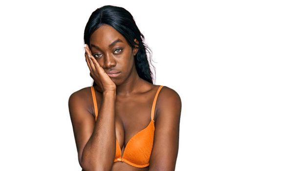 Jeune femme afro-américaine portant de la lingerie pensée fatiguée et ennuyée avec des problèmes de dépression avec les bras croisés.  - Photo, image