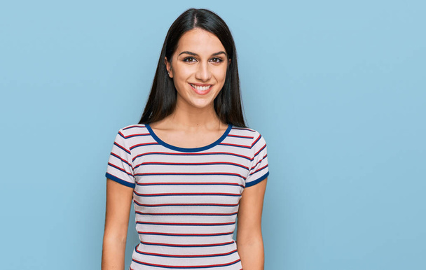 Νεαρό ισπανόφωνο κορίτσι που φοράει casual ριγέ t-shirt με χαρούμενο και δροσερό χαμόγελο στο πρόσωπο. τυχερό άτομο.  - Φωτογραφία, εικόνα
