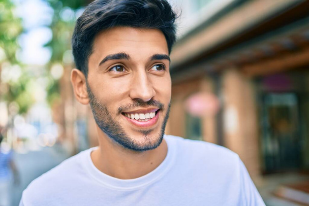 Junger lateinischer Mann lächelt glücklich durch die Stadt. - Foto, Bild