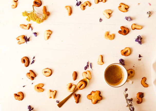 Biscuits faits maison en forme de lettre. Dans l'espace central pour mettre du texte. À côté d'une tasse de café et de fleurs de lilas sur une table blanche. - Photo, image